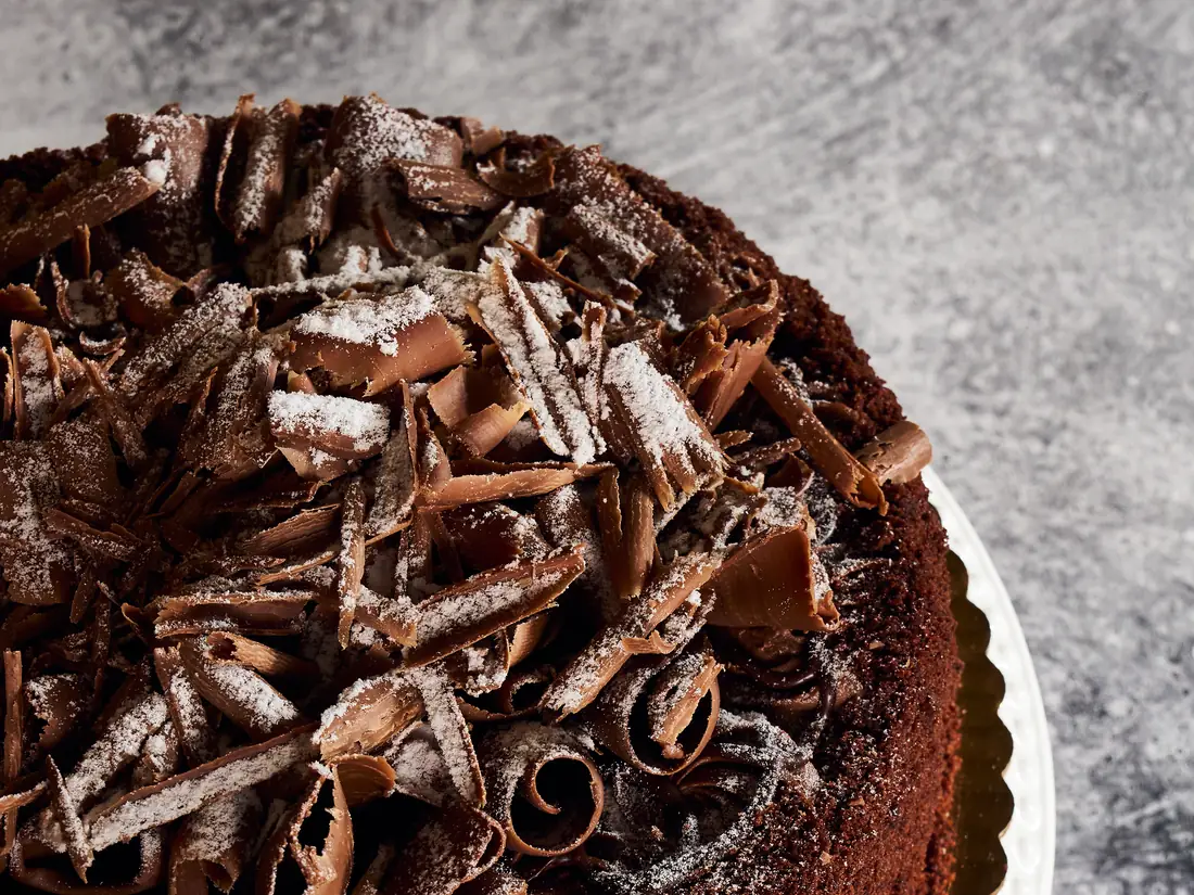 Whole chocolate cake topped with chocolate curls, from our wholesale dessert range