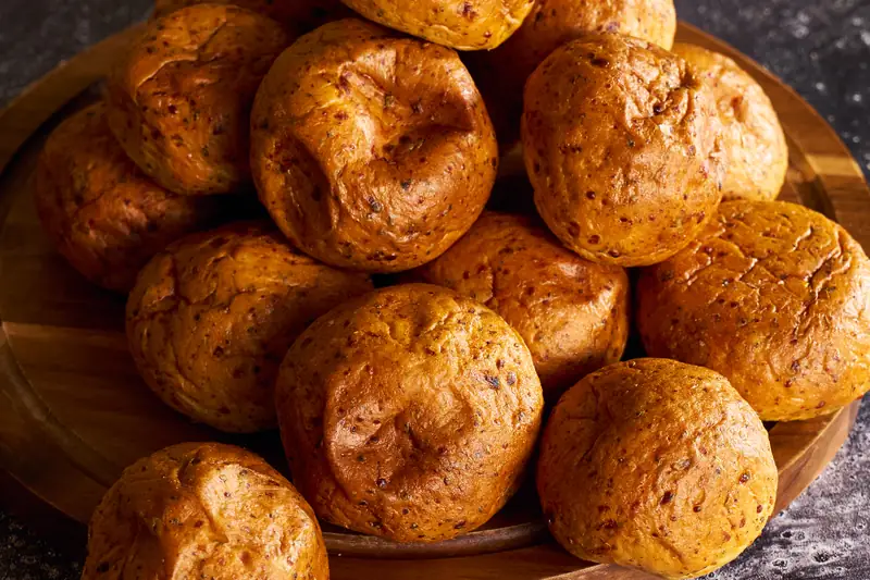 Golden dinner rolls piled on a wooden board