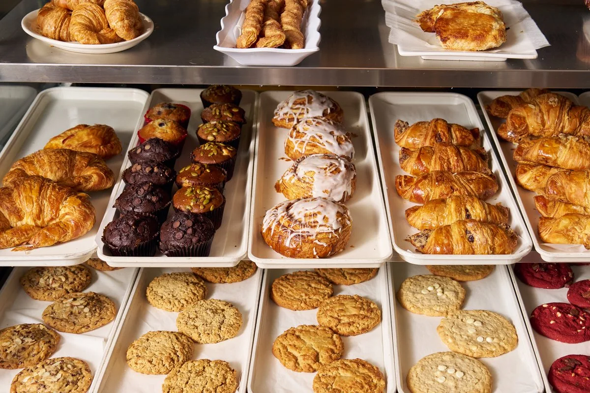 Wholesale croissants, Danish, muffins and cookies on trays in the Saffron bakery case